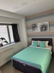 a bedroom with a bed with green sheets and a window at SpaNish apartman 6 in Niš