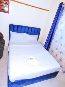 a bed with a blue headboard in a room at Stivo apartment in Nakuru