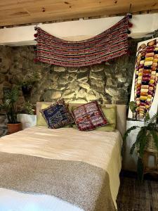 a bedroom with a stone wall and a bed with pillows at Atitlán Stone in Casa Papagayo in San Marcos La Laguna