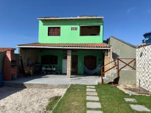a green house with a patio in front of it at Casa do Bento - Lençóis Maranheses in Santo Amaro