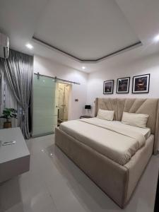 a bedroom with a large bed and a shower at 2BEDROOM FLATS - IKATE LEKKI Sapphire Apartment in Lekki