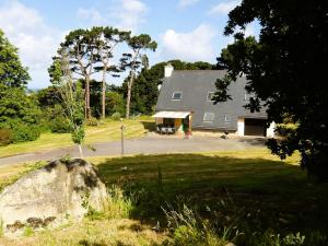 a large gray house with a large rock in front of it at Spacieuse maison familiale proche de la mer in Penvénan
