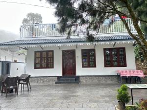 a white house with a table and chairs in front of it at The soul view homestay in Suryanelli