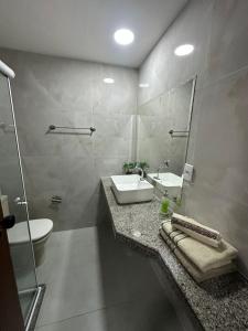 een badkamer met een wastafel, een toilet en een spiegel bij Residencial Pasárgada, apto 602 in Vila Velha