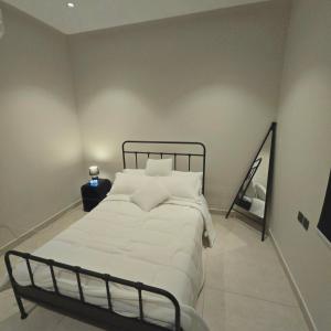 a bedroom with a bed with white sheets and a mirror at Vayan in Buraydah