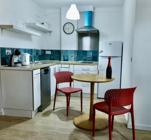 a kitchen with red chairs and a table and a clock at Cozy Seaside Apartment in Cullera in Cullera
