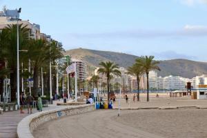 a beach with palm trees and buildings and people at Cozy Seaside Apartment in Cullera in Cullera