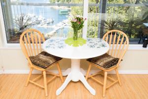 a white table with two chairs and a vase with flowers at Madeira Park Oceanview Suites in Madeira Park