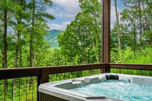 a hot tub on a balcony with a view of the mountains at Heated Pool - Luxury Cabin - Game Room - Theater in Sevierville