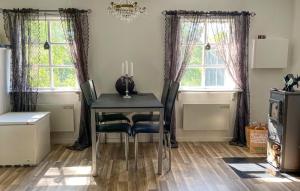 a dining room with a table and two windows at 1 Bedroom Lovely Home In Äspered in Äspered