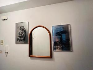 a mirror on a wall with two pictures on it at Holiday house daviale in Schisò