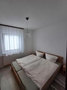 een slaapkamer met een bed met witte lakens en een raam bij Ferienwohnung Natalia in Thalfang