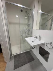 um banheiro branco com chuveiro e pia em Čenětická Apartment em Praga