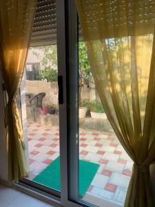 een raam met gordijnen en uitzicht op een patio bij Cosyy House in Vlorë