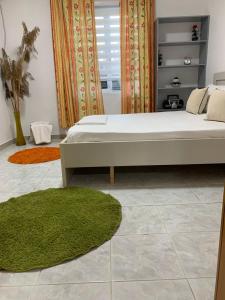 een slaapkamer met een groot bed en een groen tapijt bij Cosyy House in Vlorë