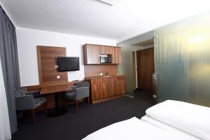 um quarto de hotel com uma secretária, uma televisão e uma cama em Pension am Kurpark em Viena