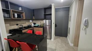 een keuken met een zwart aanrecht en rode stoelen bij Inmejorable ubicación 2D2B, con estacionamiento in Los Ángeles