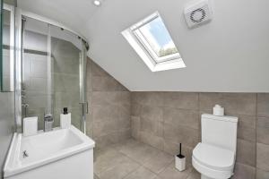 a bathroom with a toilet and a sink and a skylight at Spacious 4BDR House By Homestyles Hosts Short Lets & Serviced Accommodation Suffolk With Private En-Suite & Free Parking in Ipswich +33 photos