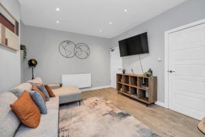 a living room with a couch and a flat screen tv at Spacious 4BDR House By Homestyles Hosts Short Lets & Serviced Accommodation Suffolk With Private En-Suite & Free Parking in Ipswich