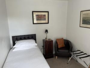un dormitorio con una cama y una silla en The Coach House, en Bodmin