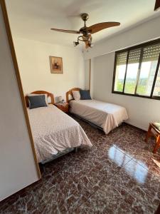 ein Schlafzimmer mit zwei Betten und einem Deckenventilator in der Unterkunft Apartamento Acogedor con Piscina, Cerca de la Playa in Playa de Gandia + 35 Fotos