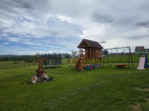 two people sitting in a field with a playground at Stramówka in Groń