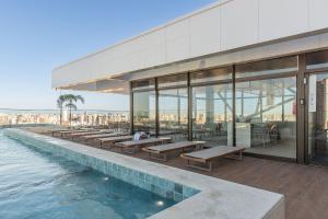 a building with a swimming pool with tables and benches at Beach Class Meireles #1505 Vista Mar By Carpediem in Fortaleza