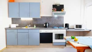 a kitchen with blue cabinets and a stove top oven at Pension BRUNI in Oberbach