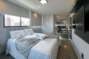 a bedroom with a bed with white sheets and a television at Studio Luxo 150m Praia Intermares 3 Pessoas in Ilha da Restinga +15 photos