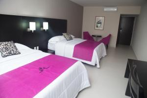 a hotel room with two beds with pink and white sheets at Hotel HAUS Ixtaczoquitlán in Orizaba