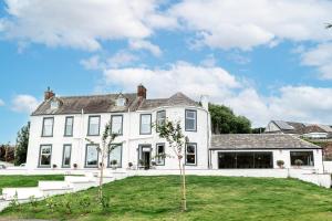 a white house with trees in the yard at Torr House Hotel in Dumfries