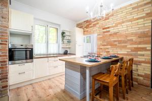 a kitchen with white cabinets and a brick wall at Apartman Harmónia in Nové Zámky