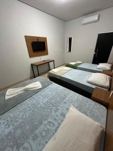 a hotel room with two beds and a flat screen tv at Hotel Manarela in Imperatriz