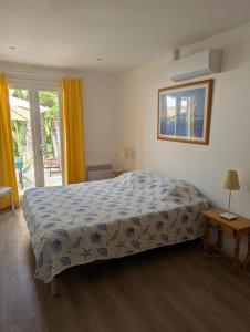 a bedroom with a bed with a blue blanket and a window at Le Mas de la Palmeraie - Mas 3 dans propriété privée au calme avec piscine et tennis in Bormes-les-Mimosas