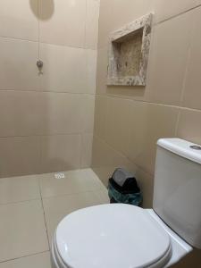 a white toilet in a bathroom with a hole in the wall at Hotel Manarela in Imperatriz