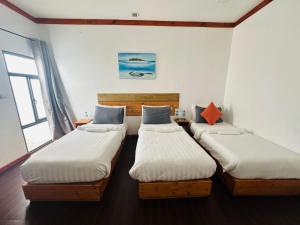 a room with three twin beds in it at Palm Grove Beach in Maafushi
