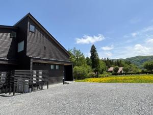 a black house with a bench in front of it at Kinagashi Happo Chalet - Vacation STAY 23515v in Hakuba