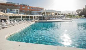 ein großes Schwimmbad mit Stühlen und einem Gebäude in der Unterkunft Terme Di Venturina in Venturina Terme