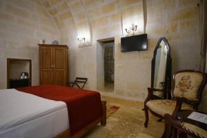 a bedroom with a bed and a tv and a chair at Kemerli House in Avanos
