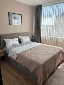 Un dormitorio con una cama grande con ventana. en 1BR Luxury apartment with sea view and parking space, en Varna