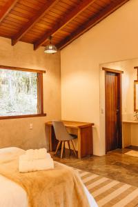 a bedroom with a bed and a desk and a chair at Ashiyana Brasil in Alto Paraíso de Goiás