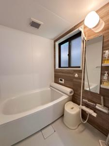 a bathroom with a tub and a toilet and a sink at Mine House Noritake Shinmachi - Vacation STAY 24243v in Nagoya +81 photos