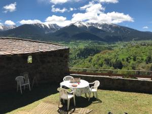 a table and chairs on a patio with mountains in the background at Family Cottage with a View in Mont-Louis