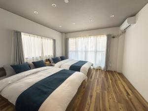 two beds in a room with wooden floors and windows at Mine House Noritake Shinmachi - Vacation STAY 24243v in Nagoya