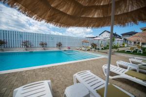a swimming pool with chairs and an umbrella at Alma Rezidence in Turda