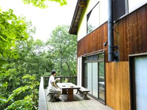 a man sitting on the deck of a house at Forest Waltz - Vacation STAY 26221v in Komoro