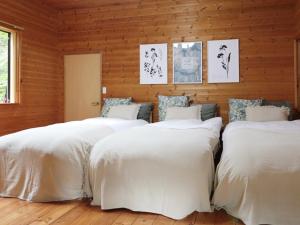 three beds in a room with wooden walls at Forest Waltz - Vacation STAY 26221v in Komoro