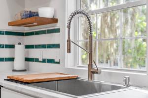 a kitchen sink with a wooden cutting board next to a window at Oystershell Cottage in Port Royal +41 photos