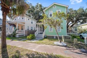 a green house and a white house with a tree at Oystershell Cottage in Port Royal