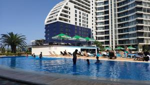 a group of people in a swimming pool with buildings at Stylish apartments White Sails View in Batumi